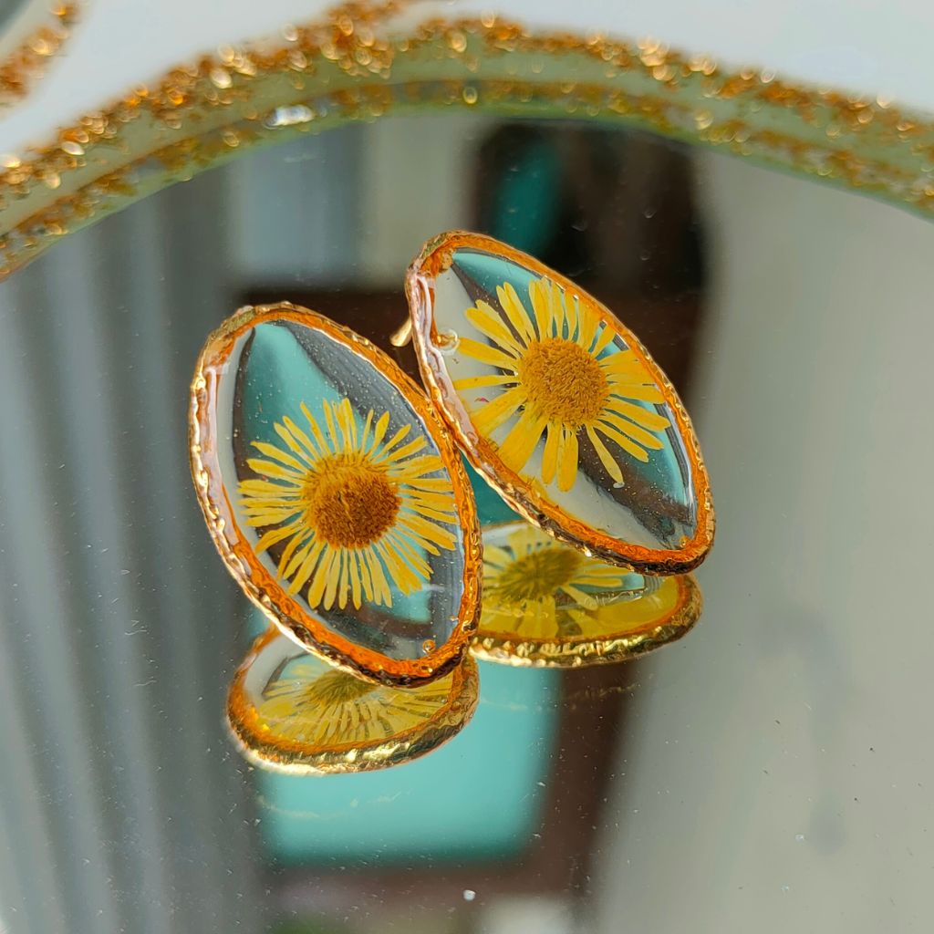 Flat-lay display of Embracing The Dawn real dried flower earrings showing resin shine and metal posts