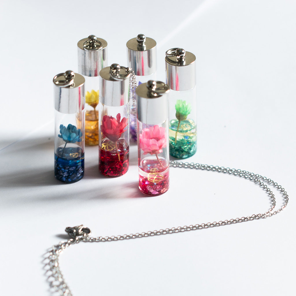 All six Lyrical Lotus necklaces in pink, blue, red, green, purple, and yellow resin variants displayed together