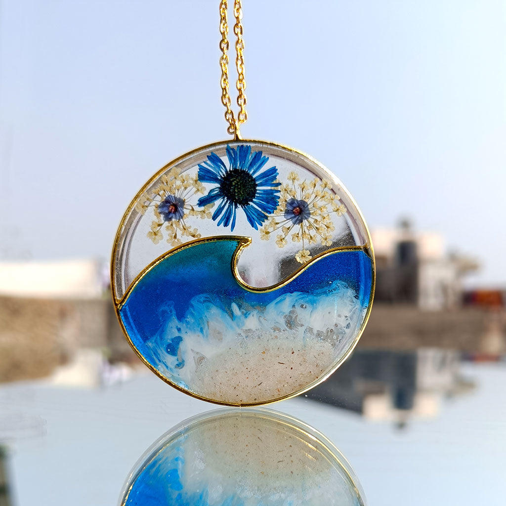 Close-up of Ocean Crest real dried flower resin pendant necklace with gold bezel
