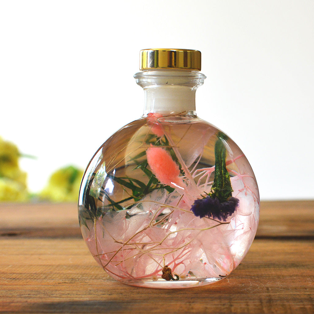 Close-up of Swirling Salmon Preserved Flower Tabletop by myBageecha – peach-toned preserved blooms in round bottle.