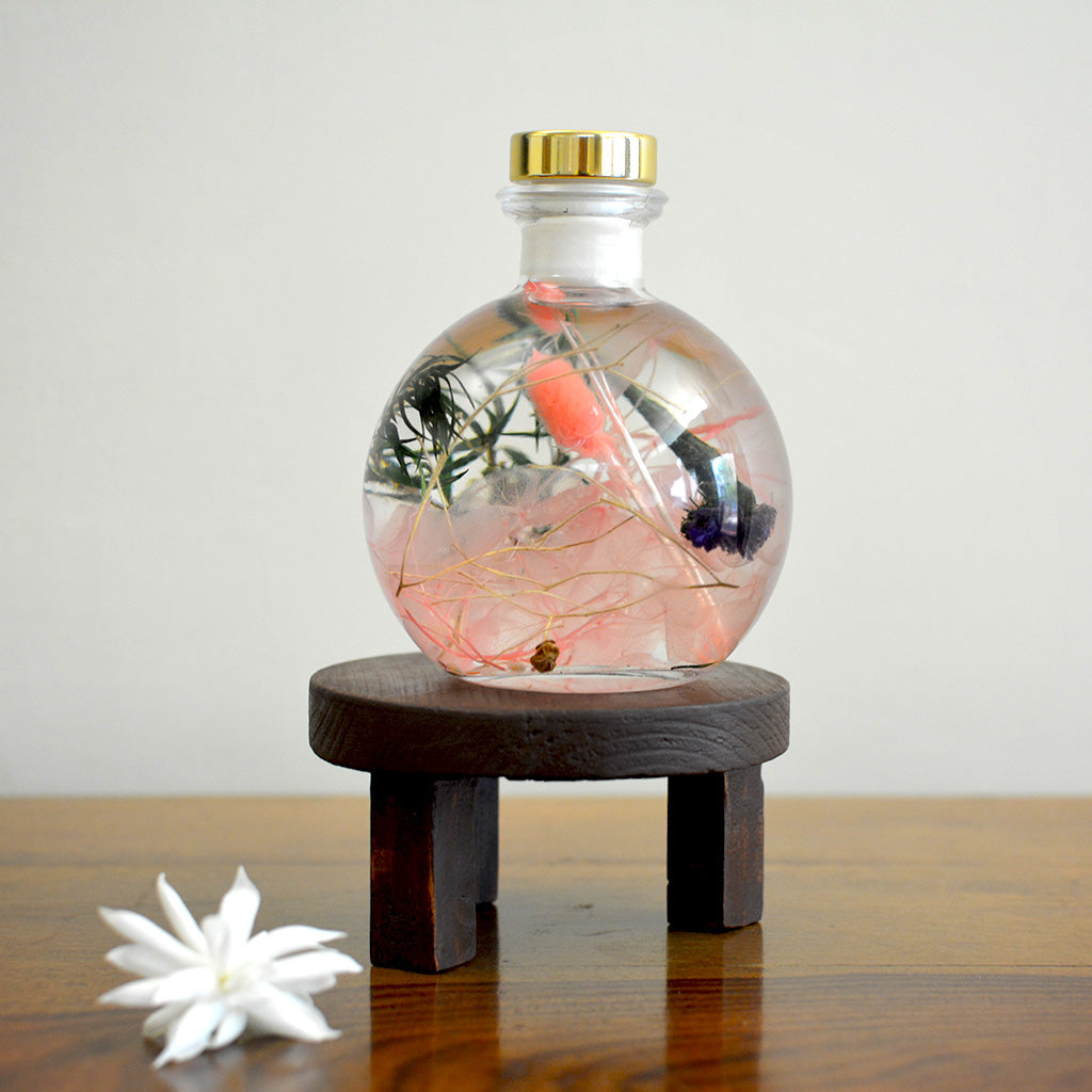 Swirling Salmon Preserved Flower Tabletop on circular stand – subtle and warm preserved arrangement.