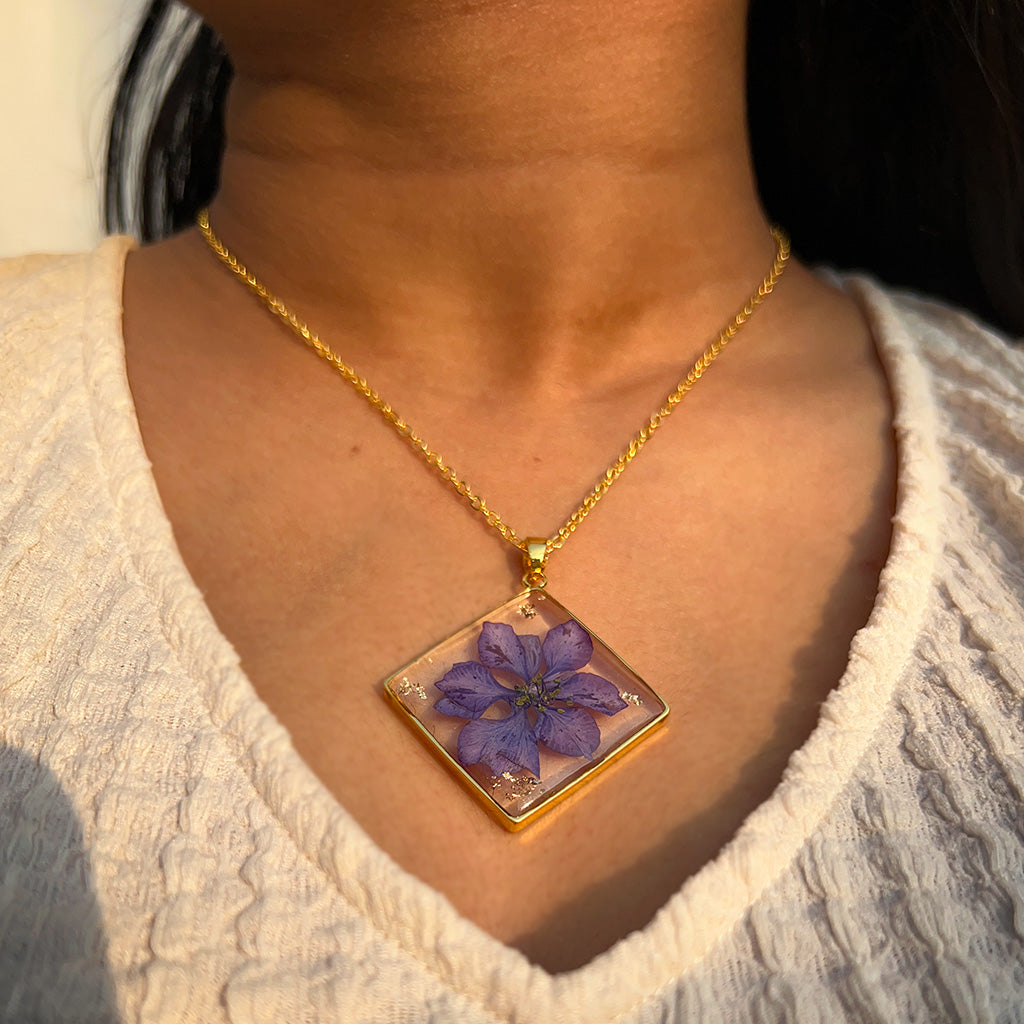 Neck close-up of Wisteria Whispers botanical resin necklace featuring preserved purple blossoms