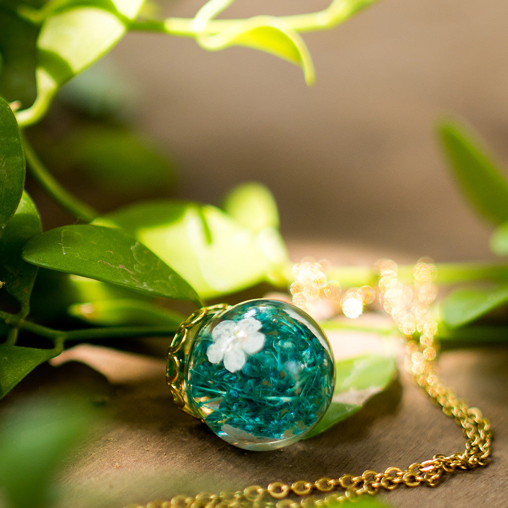 Close-up of Boscage Tangle resin pendant showing real dried leaves encased in transparent resin