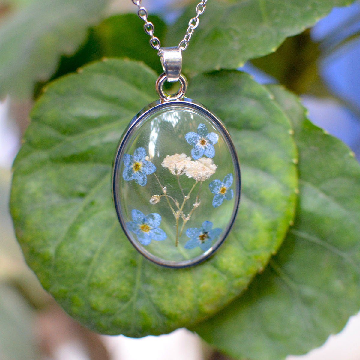 Celestial-inspired handcrafted resin pendant necklace featuring tiny real preserved blossoms