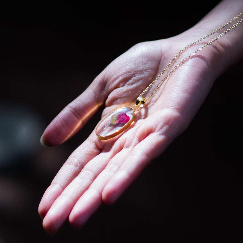 A Delicate Rosette resin pendant necklace resting on woman’s palm highlighting natural floral beauty