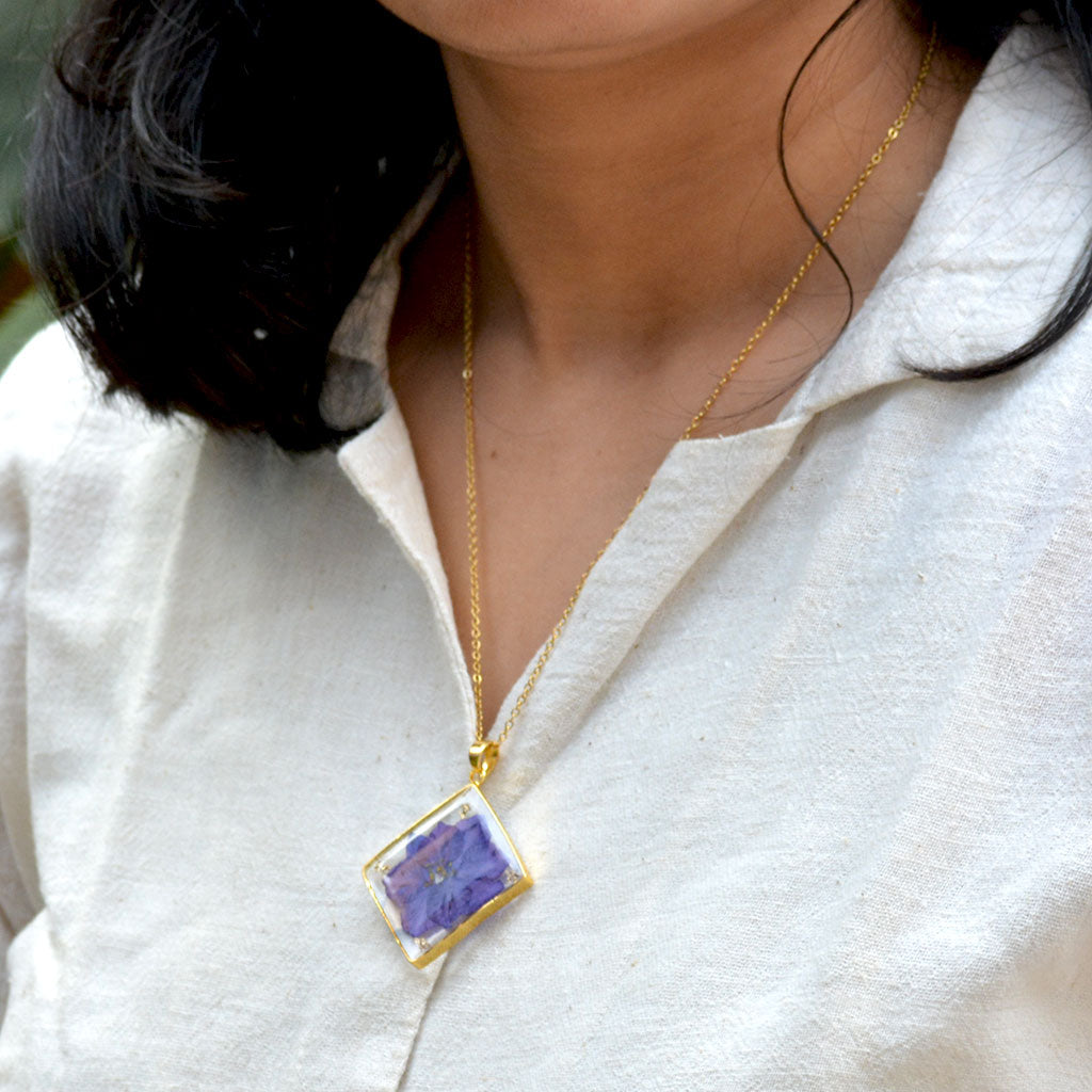 Woman wearing Wisteria Whispers real dried flower resin necklace showcasing elegant lavender tones