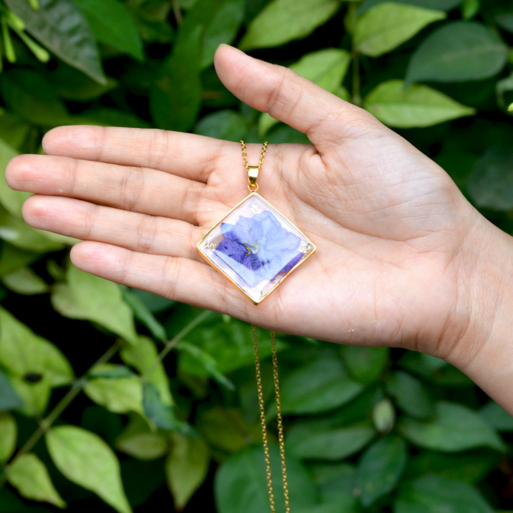 Wisteria Whispers resin pendant necklace resting on woman’s palm highlighting delicate handcrafted design