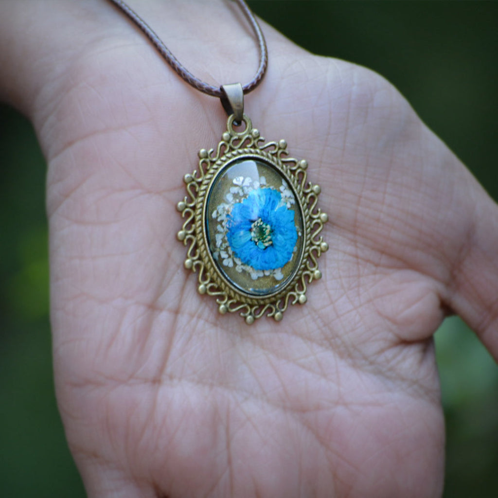 Azure Fantasia resin pendant resting on woman’s palm showing delicate handcrafted floral detail